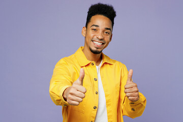 Wall Mural - Young fun smiling man of African American ethnicity wear yellow shirt t-shirt showing thumb up like gesture isolated on plain pastel light purple background studio portrait. People lifestyle concept.