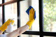 © kamiphotos - Person cleaning the room, cleaning staff is using cloth and spraying disinfectant to wipe the glass in the company office room. Cleaning staff. Maintaining cleanliness in the organization.
