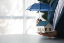 Individuals Holding Small Umbrellas And Model Homes, Housing Insurance Against Impending Loss And Fire, Building Fire Insurance, Home And Real Estate Insurance Concepts.