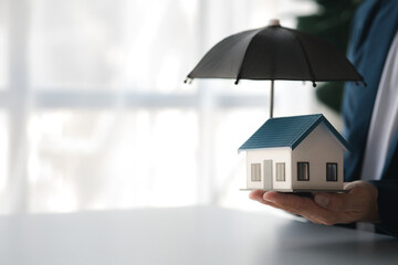 Individuals holding small umbrellas and model homes, housing insurance against impending loss and fire, building fire insurance, home and real estate insurance concepts.