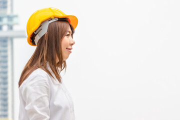 Young architect woman in yellow helmet standing at the city, Female engineer at building construction site