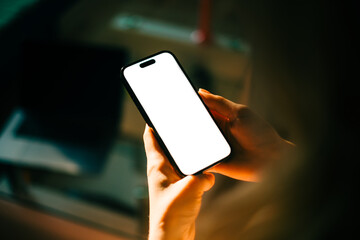 woman holding mobile phone with white screen mock up, resting on a sofa in living room at home.