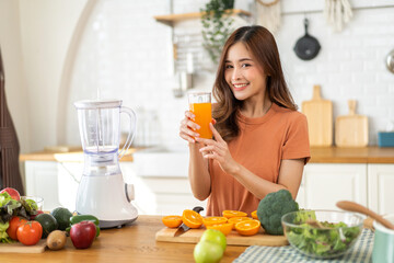 Portrait of beauty body slim healthy asian woman drinking glass of juice and orange.young girl preparing cooking healthy drink with fresh orange juice in kitchen at home.Diet concept.healthy drink