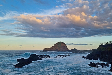 Wall Mural - A turquoise wave crashes against the rocks and the coast. The background of nature.