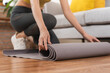 © KMPZZZ - Workout, hobby asian young woman folding, rolling gray rubber carpet, fitness mat to keep after yoga session finished,  training in class, room at home. Healthy fitness exercise, sport for wellbeing.