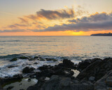 Fototapeta Niebo - dramatic sunrise at the sea. rocky coast and cloudy sky