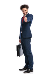 happy elegant businessman smiling, holding suitcase and making thumbs up gesture