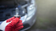 The hand of the master holds a halogen light bulb against the background of the car.Replacing the light bulb in the car.Replacement of lighting.