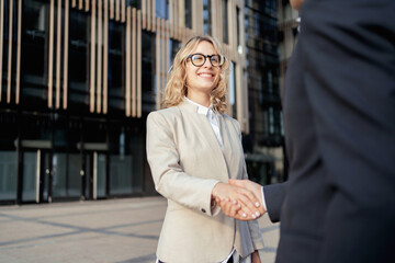 Blonde woman business meeting with colleague greeting gesture. A manager going to work wearing glasses.