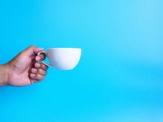 Wall Mural - Man hand holding a white coffee cup, filled with hot black coffee(americano), no sugar no milk, ready to drink, refreshing. aroma awake fresh to work placed on a blue isolated background