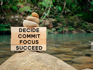 Wall Mural - Inspirational and motivational words of decide commit focus succeed on wooden blocks with blurred nature background.