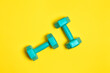 © esvetleishaya - Two bright blue or mint dumbbells are isolated on yellow background. Sport and health concept.