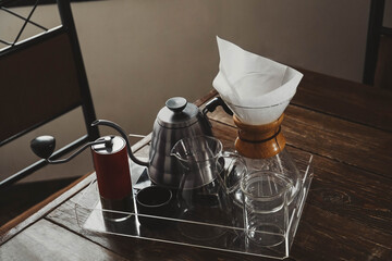 Poster - Coffee maker, grinder and kettle on wooden table in cafe