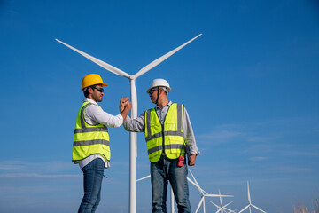 Engineer wearing uniform hold equipment box inspection work in wind turbine farms rotation to generate electricity energy. Green ecological power energy generation wind sustainable energy concept.