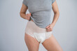 © Михаил Решетников - Woman in adult diapers and gray t-shirt on a white background. Incontinence problem.