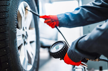 Wall Mural - inflating tire and checking air pressure use gauge in mechanics hands. Car service, checking vehicle