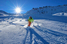 Austria, Tyrol, Sun Shining Over Female Skier Sliding Down Snowcapped Slope In Tux Alps