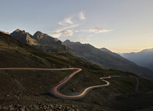 Austria, Vehicle Light Trails Stretching Along Winding Mountain Pass In Alps