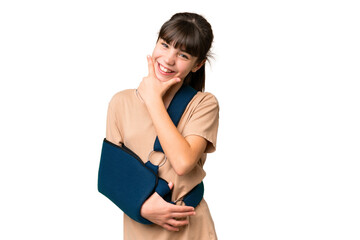 Wall Mural - Little caucasian girl with broken arm and wearing a sling over isolated background happy and smiling