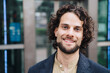 © Westend61 - Happy young businessman with curly hair outside building