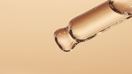 drops of essential oil fall from a glass pipette macro. cosmetic background with liquid skin care pr