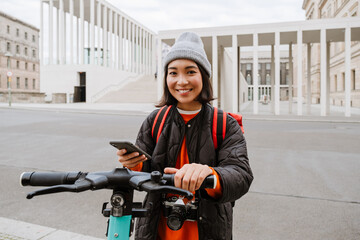 Wall Mural - Young asian woman using mobile phone for electric scooter's rent outdoors