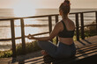 © kegfire - Relaxed young female meditating in Padmasana pose near sea
