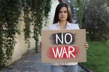 Poster - Sad woman holding poster with words No War outdoors. Space for text