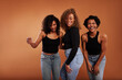 © Flamingo Images - Stylish diverse friends laughing while standing on an orange background