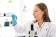 © artitwpd - Caucasian woman scientist researcher looking and holding a small Medium glass bottle for chemical analysis of liquids in the lab. Scientist working with chemical equipment in the lab.