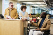 © pressmaster - Happy young female broker passing financial document to elegant African American male colleague in wheelchair during working meeting