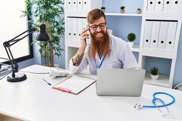 Poster - Young redhead man wearing doctor uniform talking on the telephone at clinic