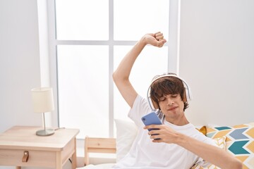 Sticker - Young blond man listening to music sitting on bed at bedroom