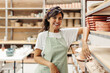 © (JLco) Julia Amaral - Happy female potter smiling at the camera in her shop