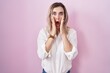 © Krakenimages.com - Young beautiful woman standing over pink background afraid and shocked, surprise and amazed expression with hands on face