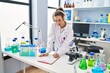 © Krakenimages.com - Young woman wearing scientist uniform listening to music writing report at laboratory