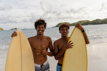 Indonesia, Lombok, Portrait Of Smiling Surfers Standing On Beach
