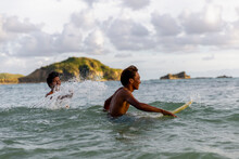 Indonesia, Lombok, Two Surfers Enjoying Surfing In Sea