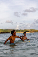 Indonesia, Lombok, Two Surfers Enjoying Surfing In Sea