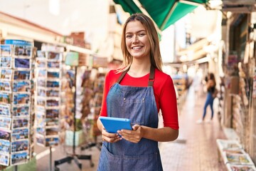 Poster - Young hispanic woman shop assistant using touchpad at street