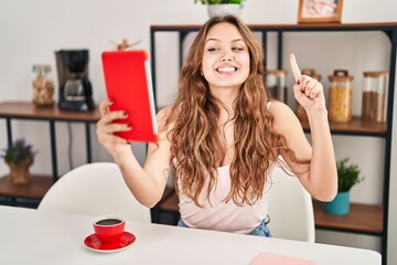 Sticker - Young hispanic woman doing video call with tablet smiling with an idea or question pointing finger with happy face, number one