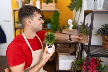 Poster - Young hispanic man florist smiling confident holding plants at flower shop