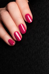 Wall Mural - Female hand with beautiful manicure - viva magenta, pink nails on black leather surface background. Nail care concept