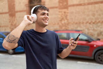 Canvas Print - Young hispanic man listening to music and dancing at street