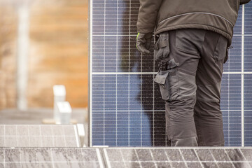 The process of installing solar panels. Solar panel installers work on the roof. Installers carry solar panel module to installation site, green and renewable energy concept