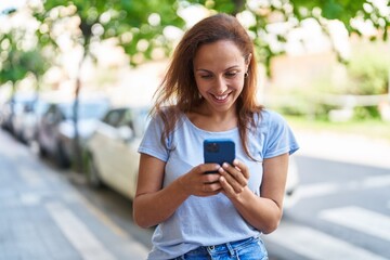 Wall Mural - Young woman smiling confident using smartphone at street