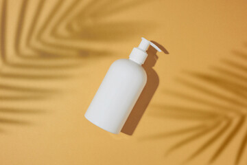 Wall Mural - Sunscreen products concept. Flat lay photo of cosmetic bottle without label tropical leaves shadow on sandy background. Summer cosmetics mockup idea.
