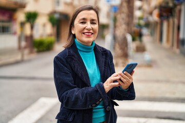 Sticker - Middle age woman business executive using smartphone at street