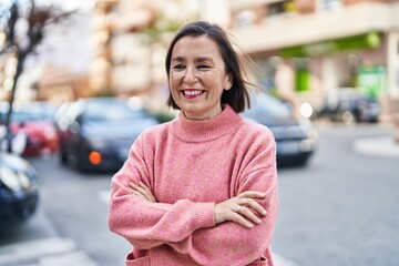 Wall Mural - Middle age woman smiling confident standing with arms crossed gesture at street