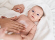© Krakenimages.com - Adorable caucasian baby lying on bed applying cream on body skin at bedroom